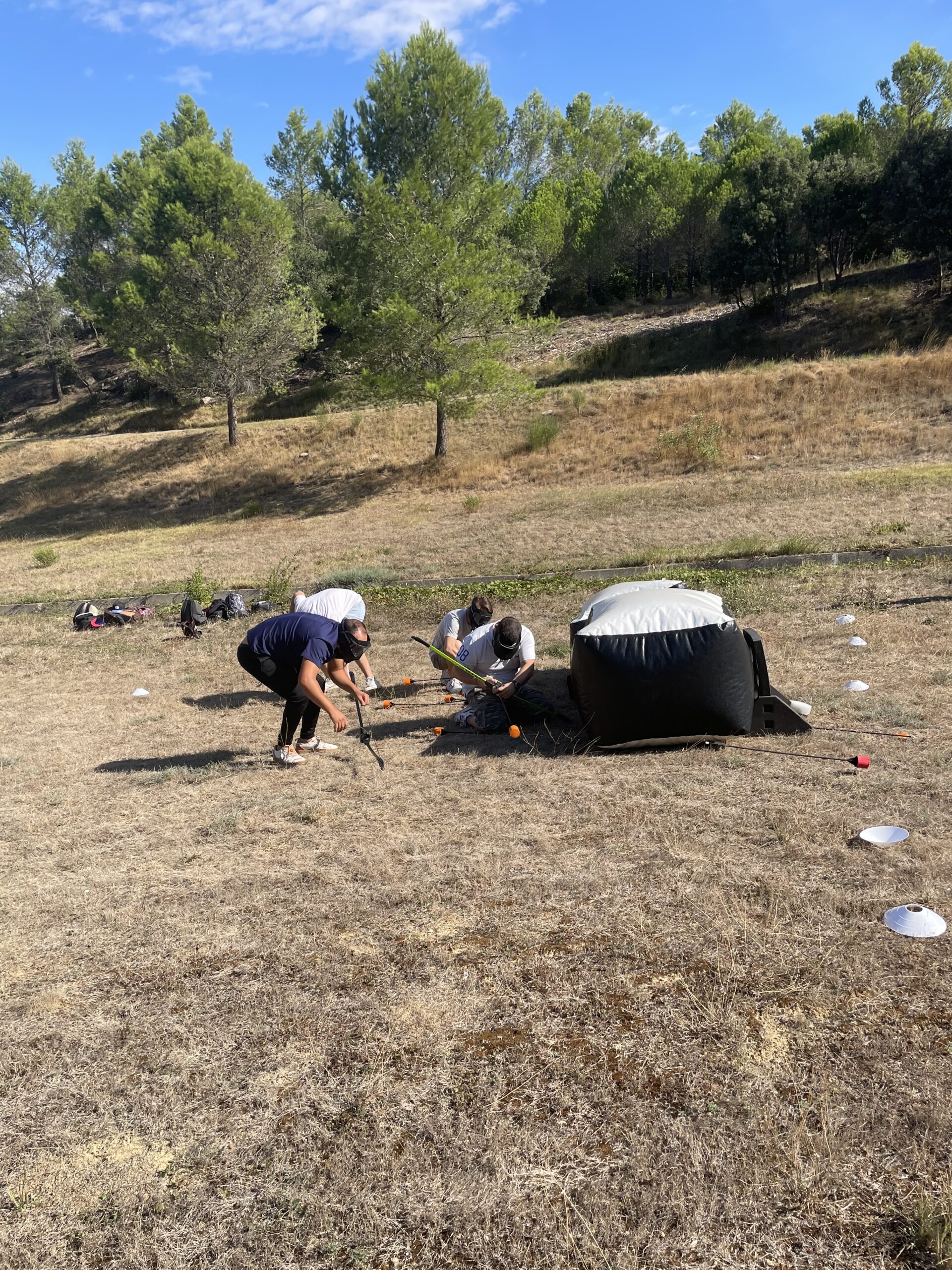 Vue d’ensemble d’un terrain d’Archery Tag, où des joueurs se cachent derrière des obstacles pour esquiver les flèches.