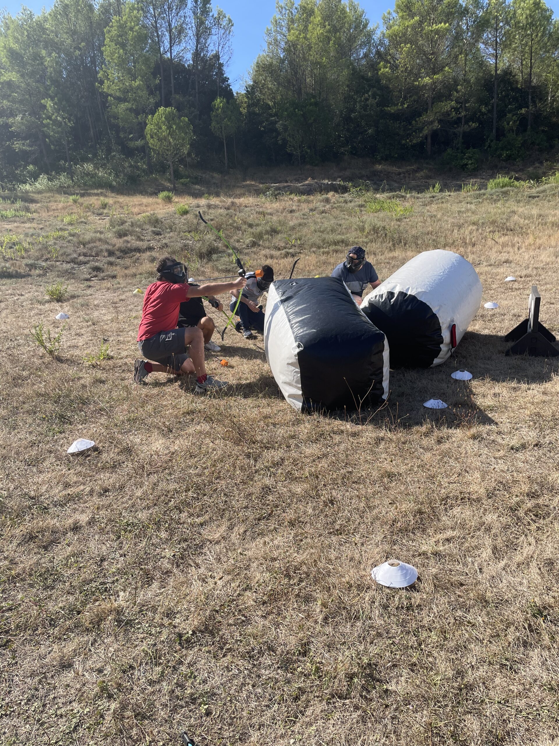 Deux participants en équipe se coordonnent derrière un abri gonflable, prêts à attaquer leurs adversaires.