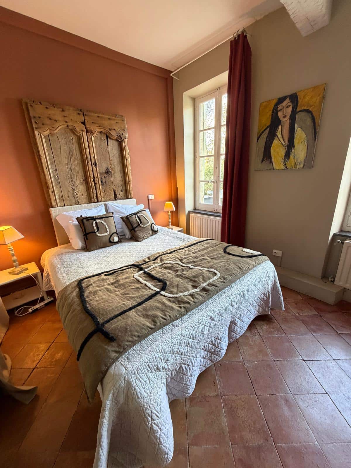 Chambre chaleureuse avec lit double et décoration artistique.